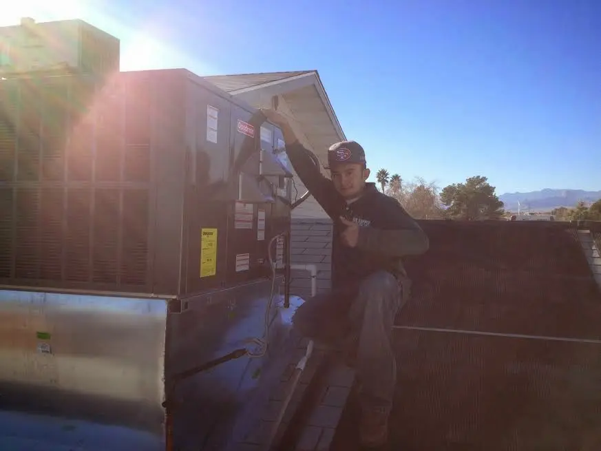HVAC technician performing Heat Pump Repair on a rooftop unit in Brighton